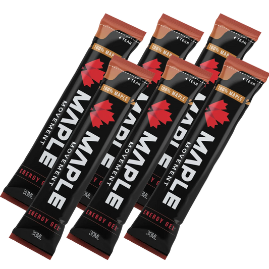 Six single-serve energy gel packets of the Maple Movement brand, arranged in a fan-like diagonal layout on a clean white background. The packets are primarily black with a bold red maple leaf logo, white text, and a brown band indicating '100% MAPLE'.