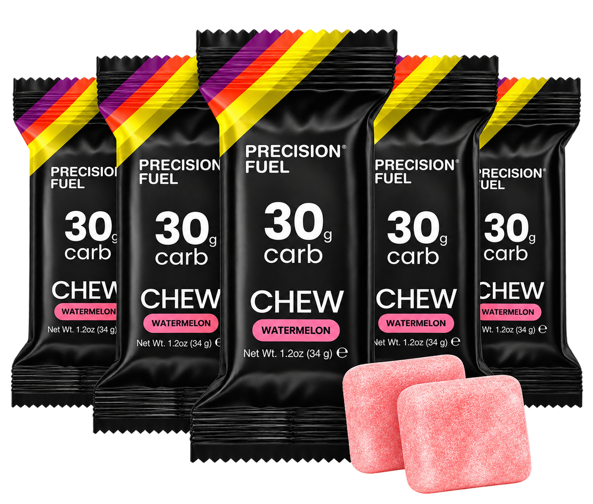 Five packs of Precision Fuel Chew gum in Watermelon flavor, arranged in a fan shape with two pink chewable tablets in front, on a solid white background.