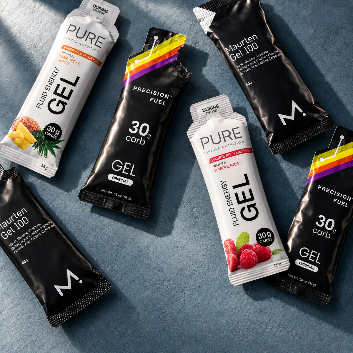 Mixed Maurten Gel 100, Precision PF 30 and PURE energy gels on a blue-grey surface